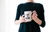 Woman in a black top holding a white mug that says ‘like a boss’