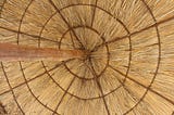 A picture taken from underneath an umbrella made of straw.