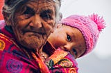 An old wizened woman with a baby peering over her shoulder