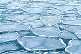 Floating plates of sea ice forming a repeating pattern with visible cracks and boundaries between them.