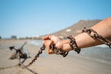 A hand in chains, pulling heavy chain tied to something far behind, dragging along the ground. Used to depict how unforgiveness is like carrying around burdens that you can simply lay down.