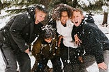 Family of four smiles and laughs in the snow.