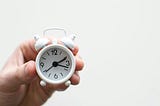 A hand holding a clock.