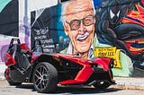 A mural featuring Stan Lee and Spider-Man dressed a black suit. Stan Lee is credited for Modern Marvel success
