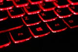 A red illuminated laptop keyboard, typical of a gaming laptop as used in casual bitcoin mining