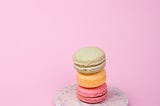 Three different color macarons on a marble plate.