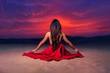 Woman meditating on a beach in a sunset