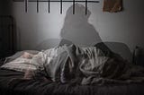 Silhouette of woman alternating between sleeping and sitting up in bed.