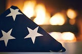 A folded flag laid before rows of flames.