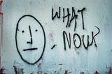 Street art depitcting an anxious face with the words ‘what now?’