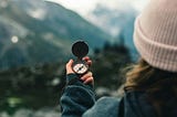 woman in the mountains looking at a compass