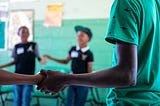 children in a classroom holding each other’s hands