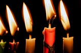 Candles burning in front of a black background