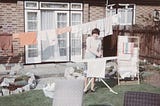 A vintage photo of a woman hanging up and ironing laundry