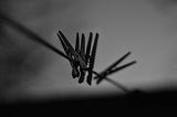 Black and white photo of clothe line with 4 clothes pins on them.