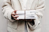 A girl holding three white blocks stacked one on top of each other, with each have a written word on it, spelling: “Spirit of Adoption”.