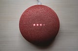 A red Google home device with LED lights turning on