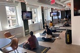 A photo of Known employees sitting on fitness mats as they attend a guided stretching session as part of Mental Health Awareness Month.