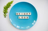 A photo of a blue plate with block words that say weight loss.