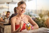 Selective Focus Photo of Smiling Woman in Red Tube Top Sitting Alone at Table Eating Dessert. What I did to break the mental barriers that kept me from enjoying a date with myself