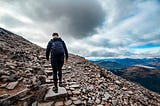 Person at the bottom of a set of stone steps, leading up a mountain