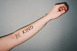 Someone’s hand with the written phrase of ‘BE KIND’