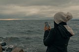 Photo of someone texting by the ocean