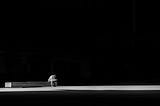 A man sitting on a bench in middle of darkness.