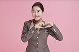 A flight stewardess smiling and making a heart with her hands.