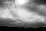 Two sets of power lines against a gray sky.