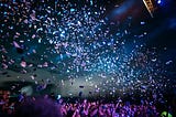 Bright blue and pink confetti tossed into a dark blue sky.