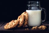 Almond milk in a lass jug and oatmeal cookies.