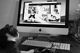 A black and white photo of a cat sitting at a computer keyboard looking at pics of cats online.