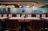 an empty booth at an old-school diner with condiments and a napkin dispenser