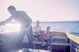 A father on a fishing boat with his two kids