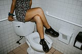 Lady sitting on toilet tank