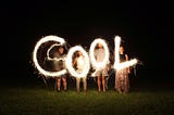 Letters COOL in bright white light with each letter held by a person