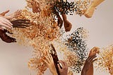 Human hands blending into abstract shapes and particles, evoking connection, transformation, and diversity.