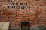 A wall which says “Until debt tear us apart”
