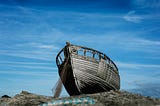 A boat on a rocky ledge which has run ashore