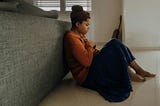 Girl sitting, back against couch, holding both hands over her heart