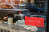 A cafe window with a red sign displaying a what3words address in Chinese