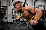 Muscular man performing push-ups on TRX bands.