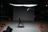 An empty set with a chair, a mic, and soft lighting waiting for someone to sit down.