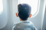Boy looking out an airplane window.