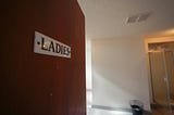 Door opening to reveal a public washroom, marked “LADIES.”