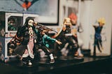 Action figures representing characters from the popular anime series Demon Slayer are arranged on a shelf in what appears to be someone’s bedroom.