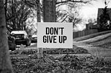 A sign with “Don’t Give Up” in bold on the front.