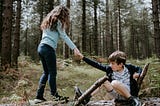 Young girl helps pull a boy up from the ground demonstrating an act of service