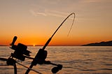 Boat-fishing rod under tension at dawn